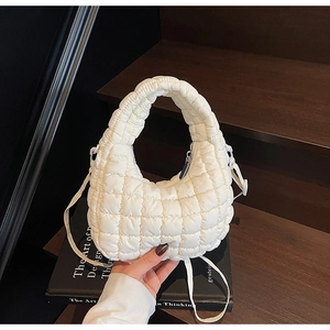 Detail of white quilted puffer crescent bag with square stitching and top handle
