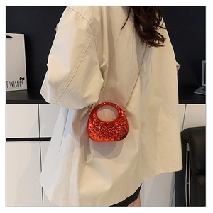 Detail of red acrylic chain bag featuring elegant diamond lattice texture and golden metal strap