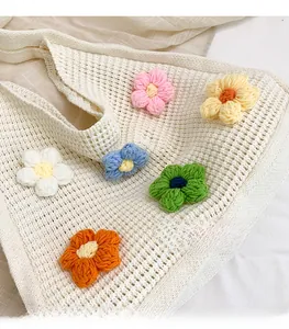 Detailed close-up of handmade crochet flowers on a beige knitted shoulder bag