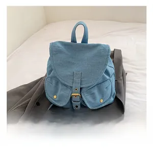 Detail of denim backpack showing large flap closure and symmetrical front pockets with snaps