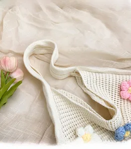 Close-up of white knitted tote bag with 3D floral crochet details and wide handle