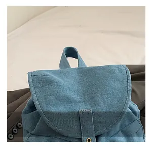 Detailed close-up of blue denim backpack showing sturdy handle and metal eyelet accents