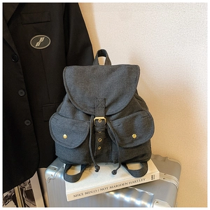 Retro denim backpack detail with large flap and pockets placed on a silver suitcase