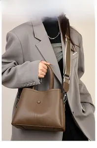 Detail of vintage brown leather handbag with adjustable wide shoulder strap on model