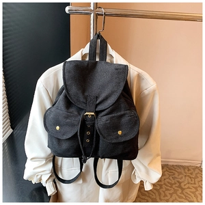 Close-up of black denim backpack with flap cover and metallic snap pockets detail