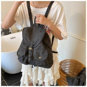 Close-up of dark grey denim backpack showing gold buckle and drawstring closure detail