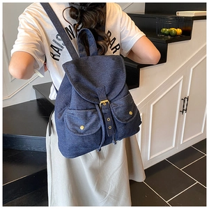 Rear view of model wearing a large dark blue denim backpack with double pockets