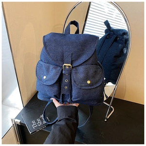 Detail of blue denim backpack showing buckle flap, front pockets and rear view in mirror