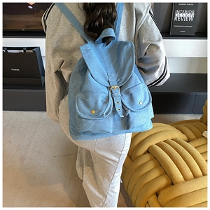 Detailed back view of a light blue denim backpack with pockets and retro gold buckles