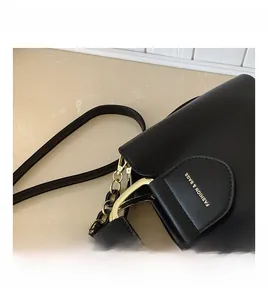 Detail of black leather bucket bag with gold metal handle and chunky chain strap