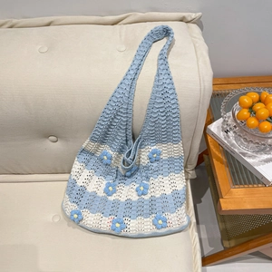 Blue and white striped crochet shoulder bag with 3D handmade flowers on a sofa