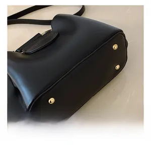 Detail view of black leather bucket bag base with four protective gold metal studs