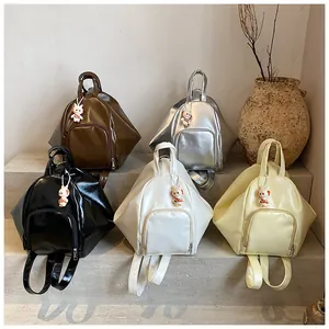 Five minimalist geometric backpacks in various colors with cute rabbit charms on display