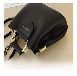 Detail of black leather bucket bag with gold metal hardware hooks and chain strap