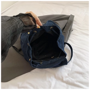 Top view of spacious denim backpack interior with black lining and golden metal eyelets
