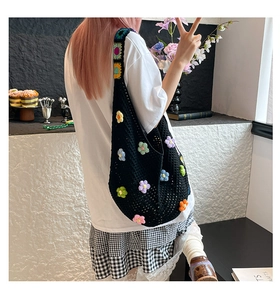 Detail einer handgefertigten schwarzen Häkeltasche mit bunten 3D-Blüten und Gurt