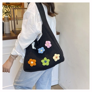 Detail of hand-knitted black tote bag with colorful 3D crochet flowers and wide strap