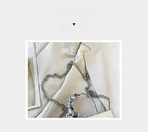 Detail of silver metallic PU handbag featuring a chunky chain and silk scarf wrapped handle