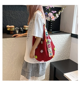 Detail der roten handgehäkelten Schultertasche mit bunten 3D-Blumenapplikationen und Gurt