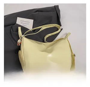 Detail of cream PU leather tote bag with panda keychain on gray blazer and book