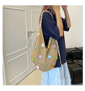 Detail einer großen handgewebten Tasche mit bunten 3D-Häkelblumen und Schultergurt