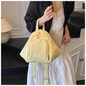 Detail of a triangle cream yellow backpack with gloss finish and cute rabbit charm on steps