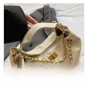 Close-up of beige quilted tote bag featuring golden metal clasp and chain strap detail