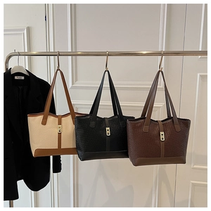 Detailed display of three woven tote bags in beige, black and brown with metal locks