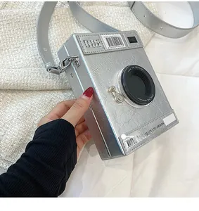 Detail of creative vintage camera-shaped crossbody bag with silver metallic finish