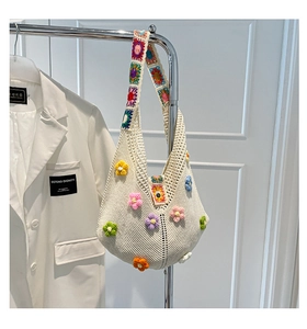 Detailed macro view of 3D crochet flowers and textured hand-knitted pattern on the tote bag