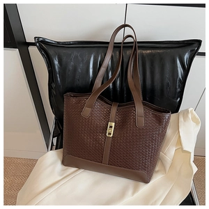 Detail of woven tote bag featuring brown PU leather texture and gold metal twist lock buckle