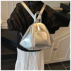 Detail of metallic silver backpack with a cute cat charm on modern indoor stairs