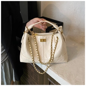 Detailed close-up of quilted cream leather bag with gold chain strap and metal lock