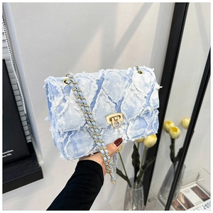 Détail du sac à chaîne en denim bleu clair avec matelassage, franges et fermoir doré