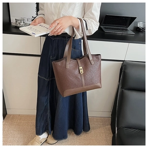 Detailed view of dark brown woven tote bag with a golden metal lock on the front