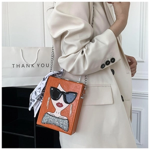 Detail of orange box bag featuring portrait art print, silver chain, and silk scarf accent