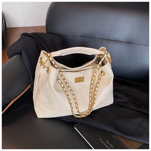 Close-up of quilted cream faux leather bag featuring a gold chain strap and turn-lock