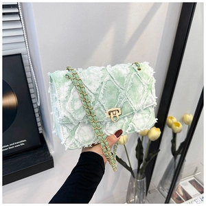 Détail de la texture denim vert clair et du fermoir doré sur le sac à bandoulière