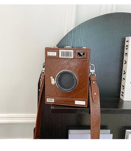 Detail of vintage camera box bag showing cracked leather texture and spotlight text