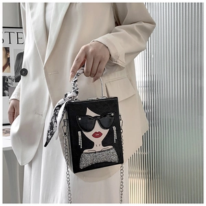 Detail of black box bag with artistic female portrait, diamond earrings and silk scarf handle