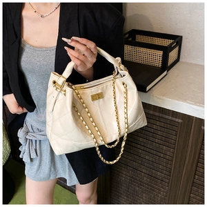 Detail of quilted leather texture and gold chain strap on cream white tote bag