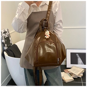 Detail view of brown glossy leather backpack with cute cat pendant in a lifestyle setting