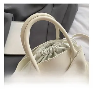 Detail of cream white handbag featuring a drawstring closure and reinforced handle