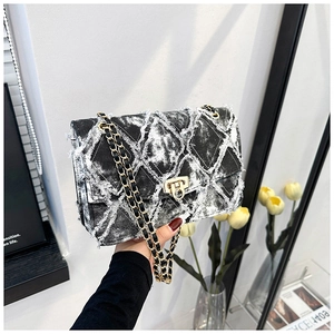 Détail du sac bandoulière en denim gris avec bords effilochés et chaîne dorée