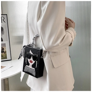 Detail of black box handbag with chic face motif and silk scarf wrapped on the handle
