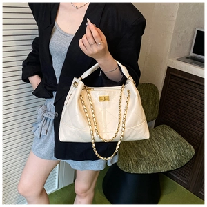 Close-up of beige quilted leather tote bag featuring gold square twist lock and chain strap