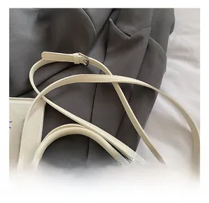Close-up of the adjustable silver buckle and cream leather strap on the stylish handbag