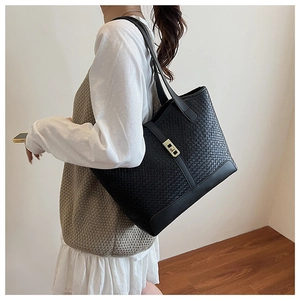 Detail of black woven tote bag featuring a gold square buckle and dual long shoulder straps