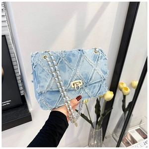 Détail du sac chaîne en denim bleu clair matelassé avec fermoir rotatif doré élégant
