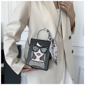 Detail of creative box bag with portrait print, metal chain, and silk scarf handle wrap